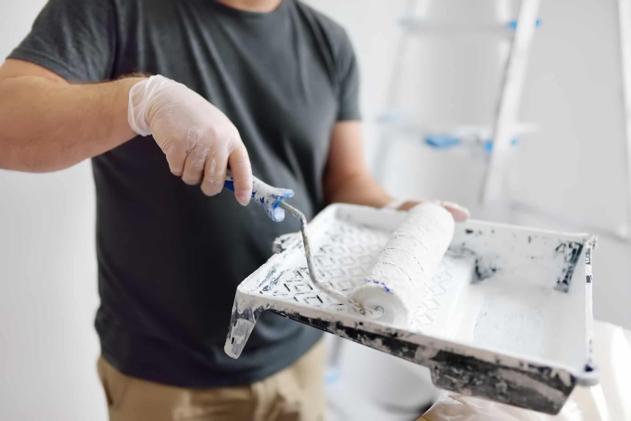 Homem com uma base com tinta e um rolo de pintura na mão