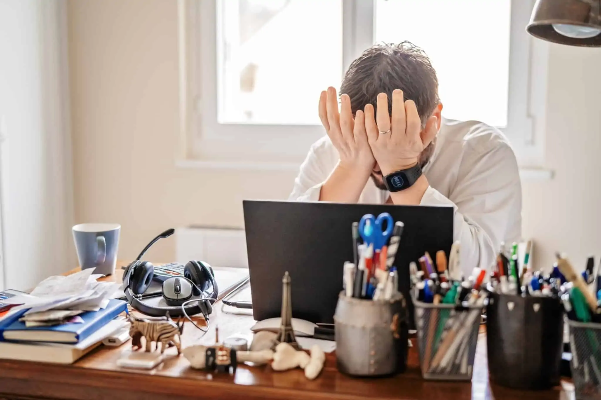 Quero demitir-me: O que devo fazer e quais os meus direitos? homem sentado em frente ao computador e de mãos na cara, num sinal de cansaço e frustração