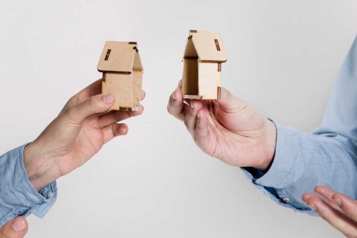 Mãos seguram duas metades de uma casa