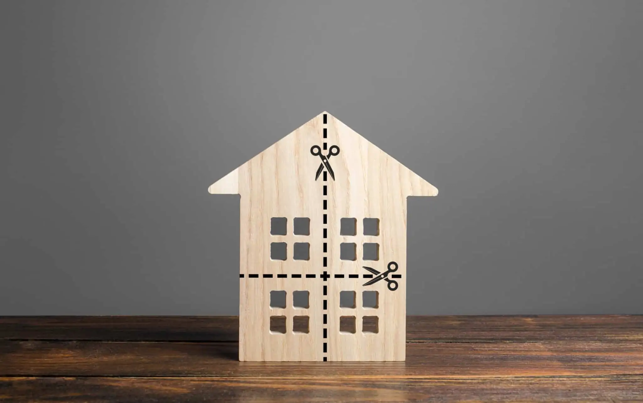 Como dividir os bens com o fim de uma união de facto? Miniatura de uma casa em madeira com picotado, sugerindo partilha de uma casa após o divórcio