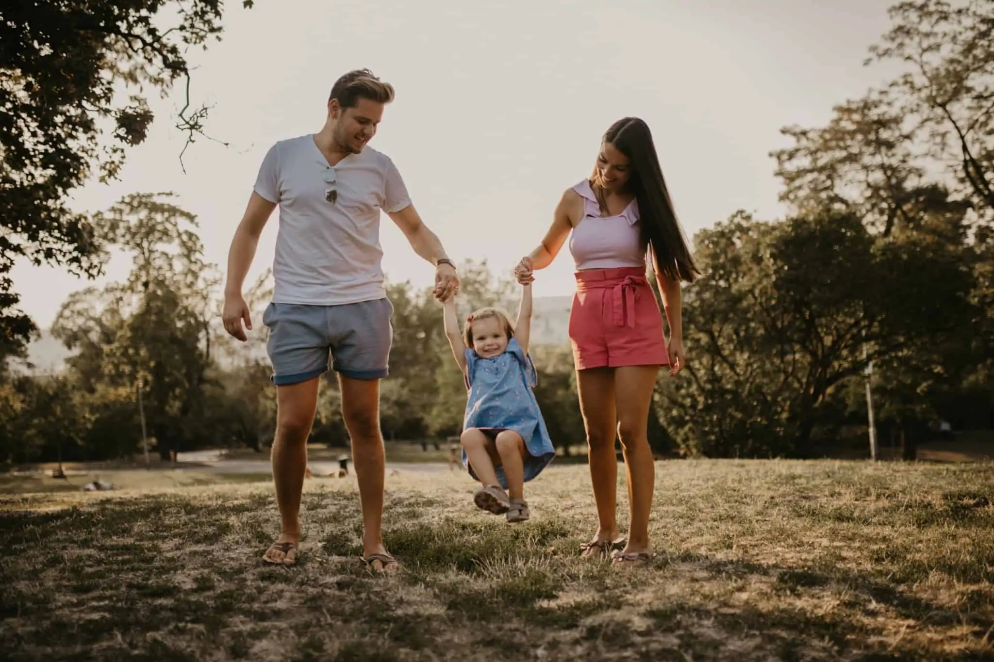 Precisa de contratar um seguro? Damos-lhe 7 dicas para poupar Família, composta pelo pai, pela mãe e por uma criança, caminham juntos enquanto brincam