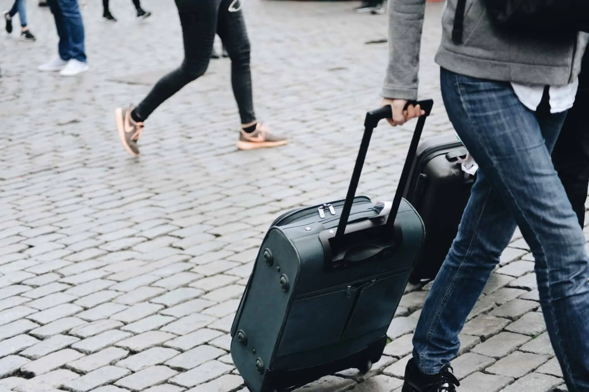 Quer tirar um ano sabático? Saiba o que deve ter em consideração Viajante arrasta uma mala de viagem por uma rua empedrada