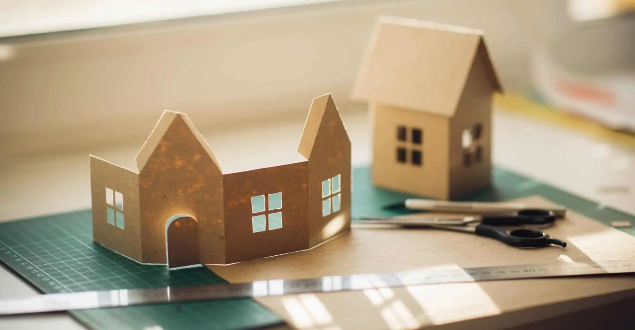Obras em casa? Há novos apoios à eficiência energética ilustra apoios à eficiência energética com uma casa de papel inacaba junto a outra terminada em cima de uma mesa