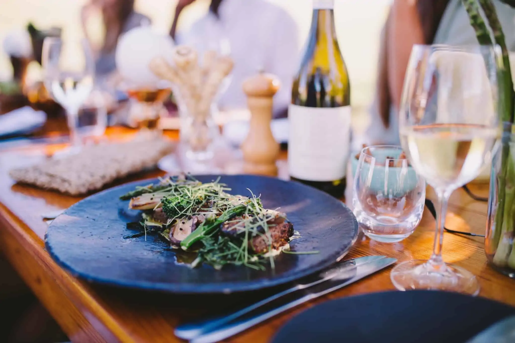 Vales de refeição: O que são e quais as vantagens? mesa num restaurante com copos de vinho e um prato com uma salada
