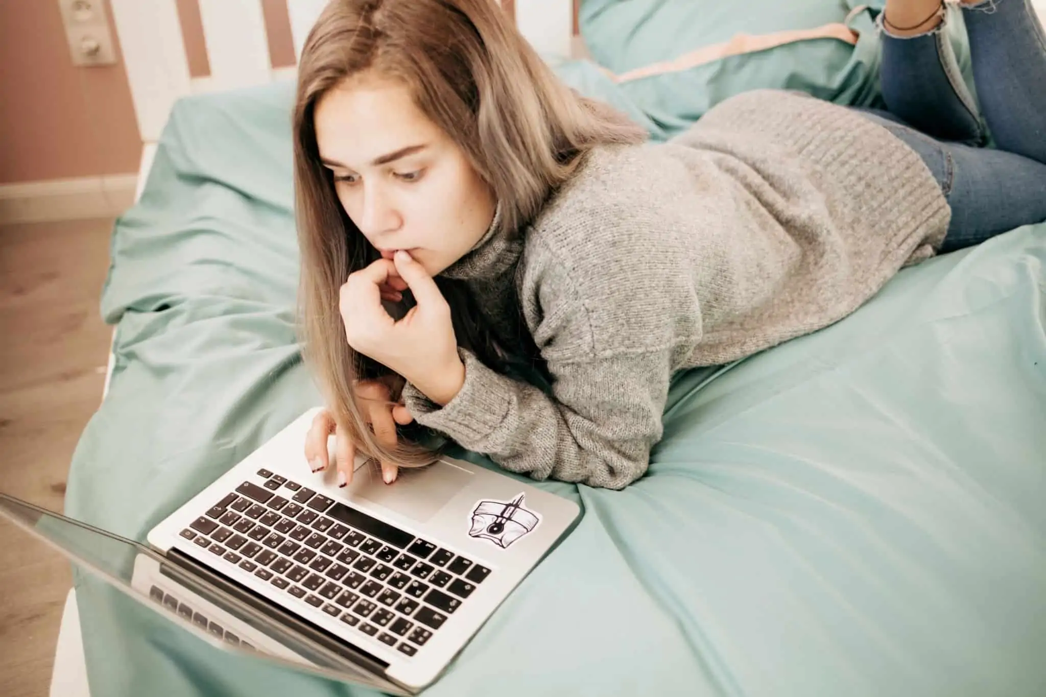 É freelancer? 37 sites que deve conhecer Rapariga deitada na cama com portátil a pensar na entrada na universidade