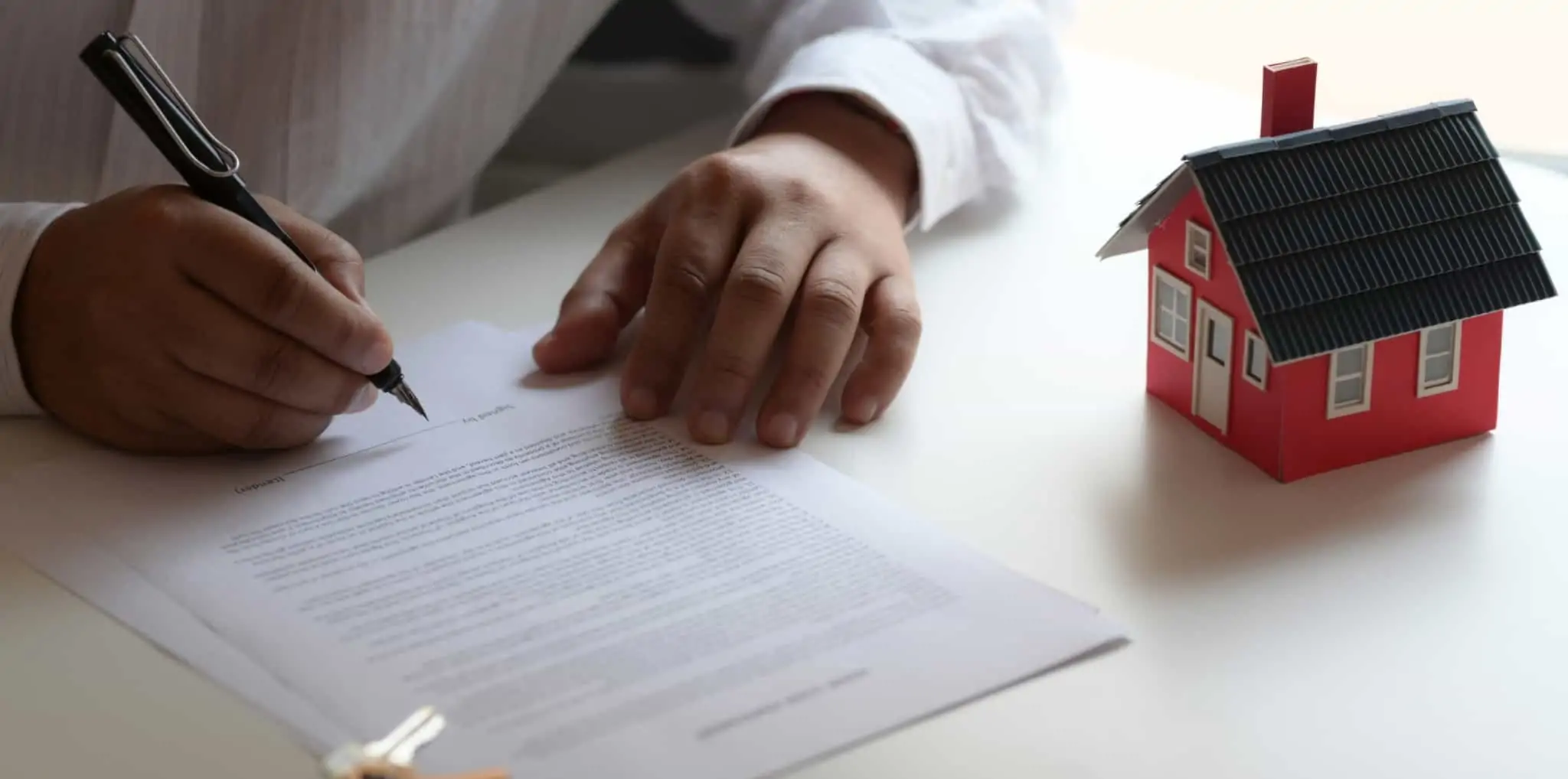 Dívidas ao condomínio: o que são, como evitar e o que fazer Homem a assinar um contrato para comprar casa, analisando as dívidas ao condomínio