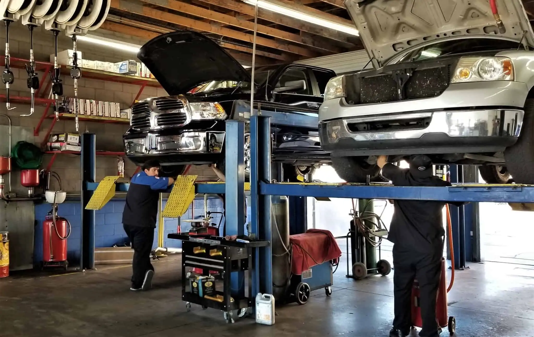 9 Dicas para reduzir as suas despesas com o carro oficina de carros com dois automóveis a serem analisados por mecânicos. A manutenção pode reduzir as despesas com o carro