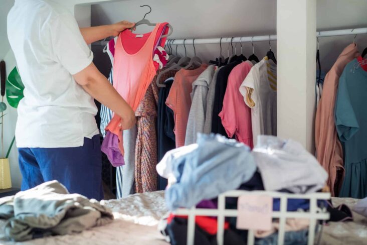 Jovem mulher a arrumar a roupa após ter descoberto 9 sites para comprar roupa barata