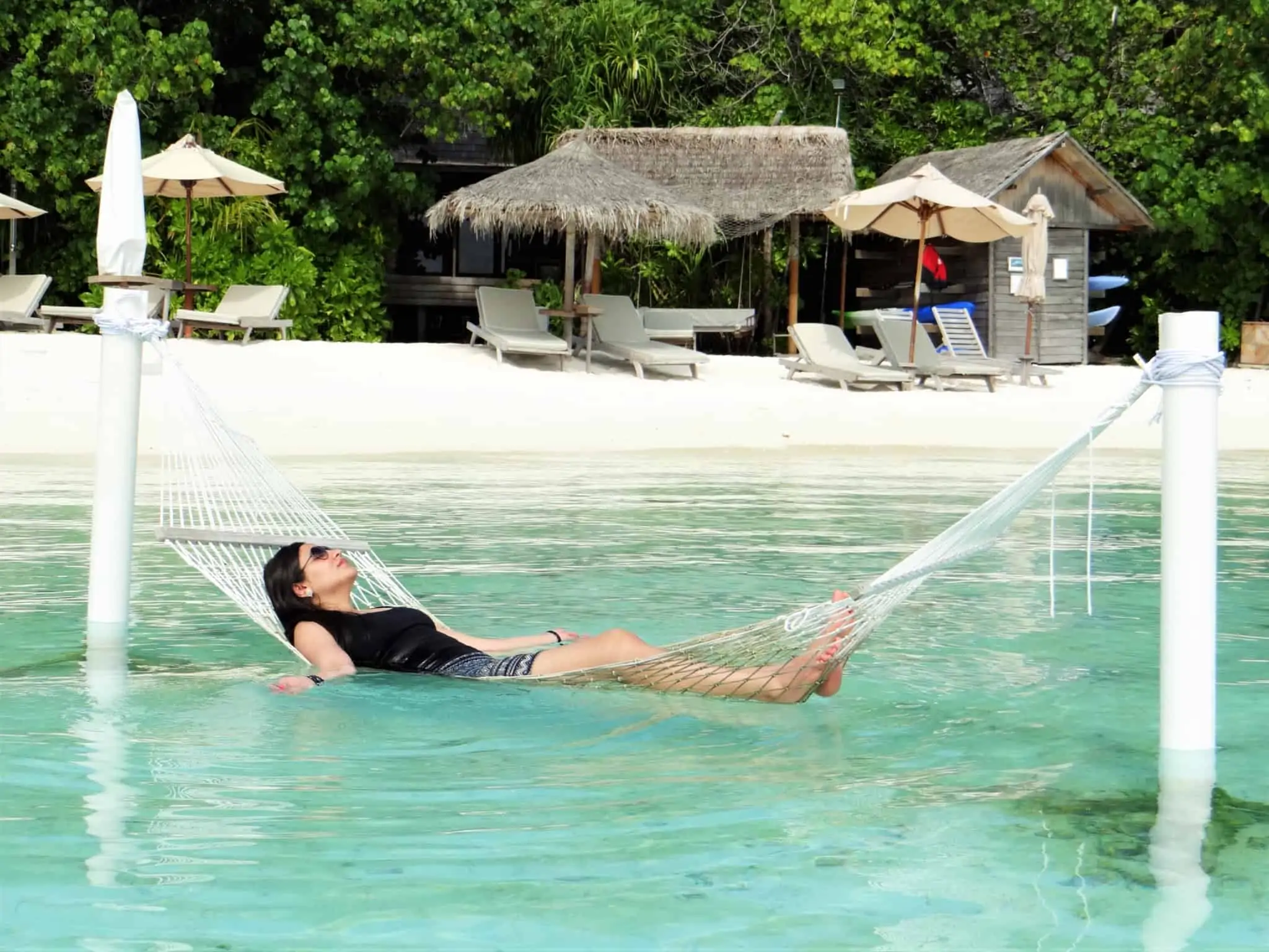 Vai de férias? 5 estratégias para desligar do trabalho A importância de desligar do trabalho em férias. Jovem mulher relaxa em cama de rede num destino paradisiaco