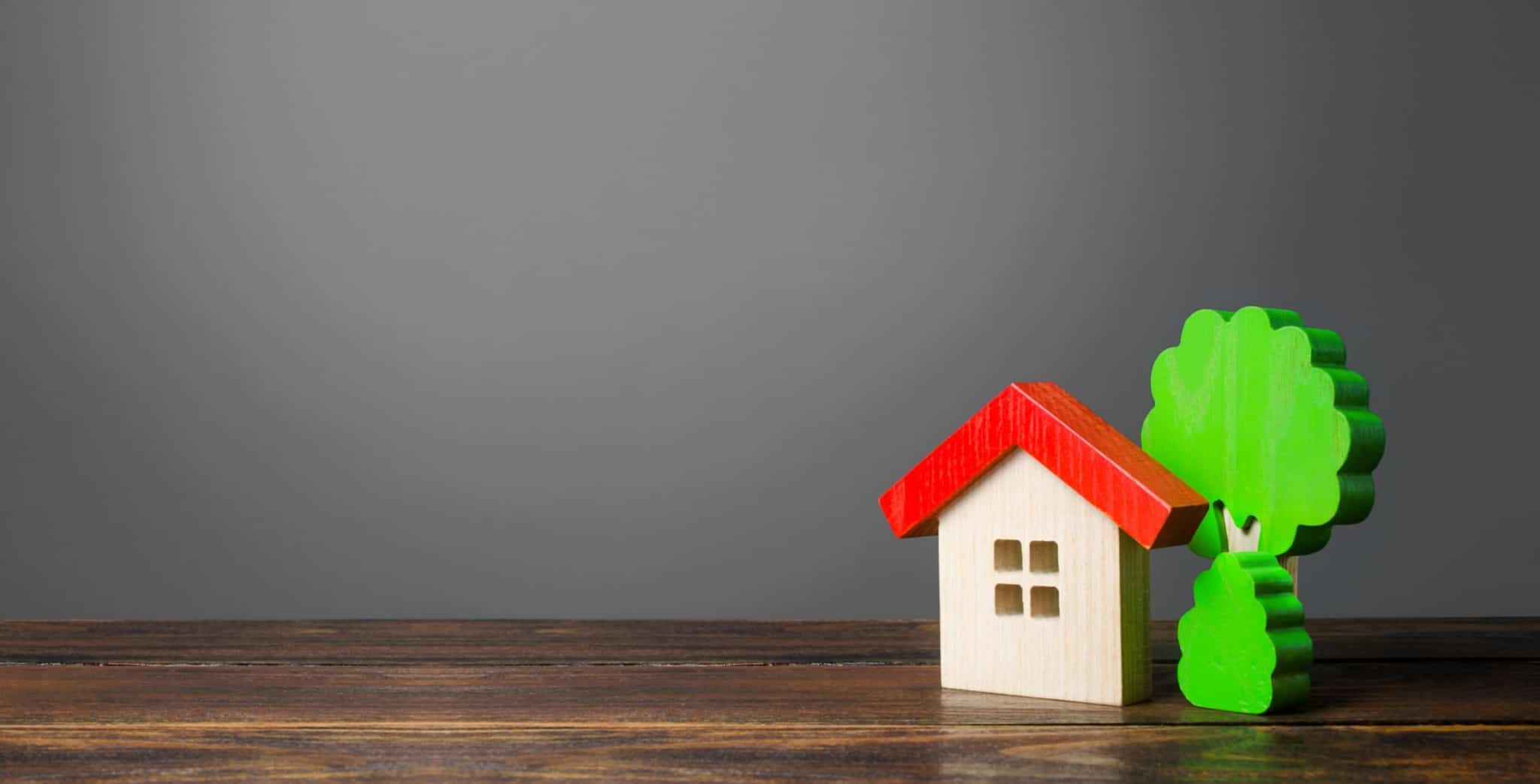 Casa de madeira em miniatura ao lado de uma árvore de madeira. A recusa de um crédito habitação pode ter várias razões