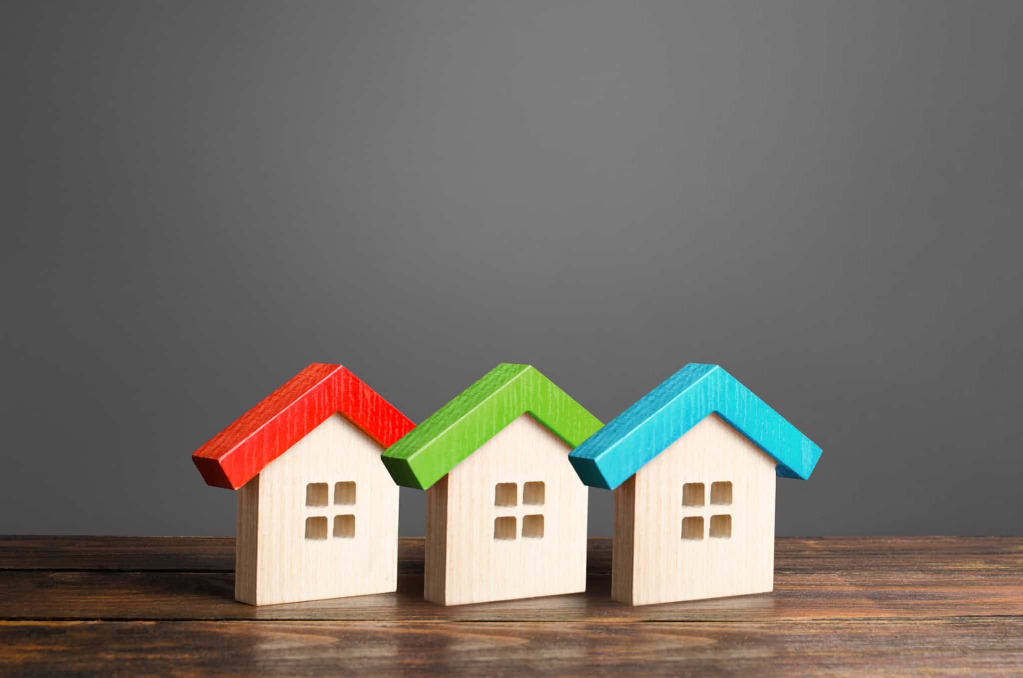 três casas de madeira em miniatura. A compra da primeira casa é um passo importante