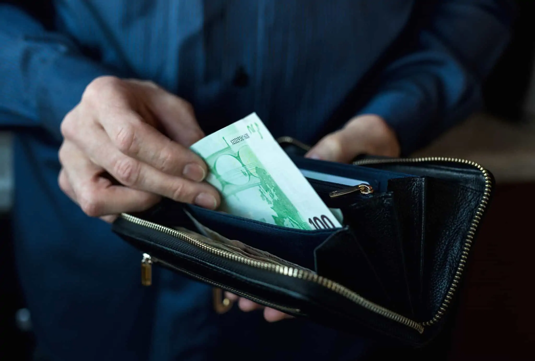 9 motivos para o seu dinheiro não chegar até ao final do mês Mãos de homem a guardar uma nota de 100 euros numa carteira, reparando que já não tem mais dinheiro até ao final do mês