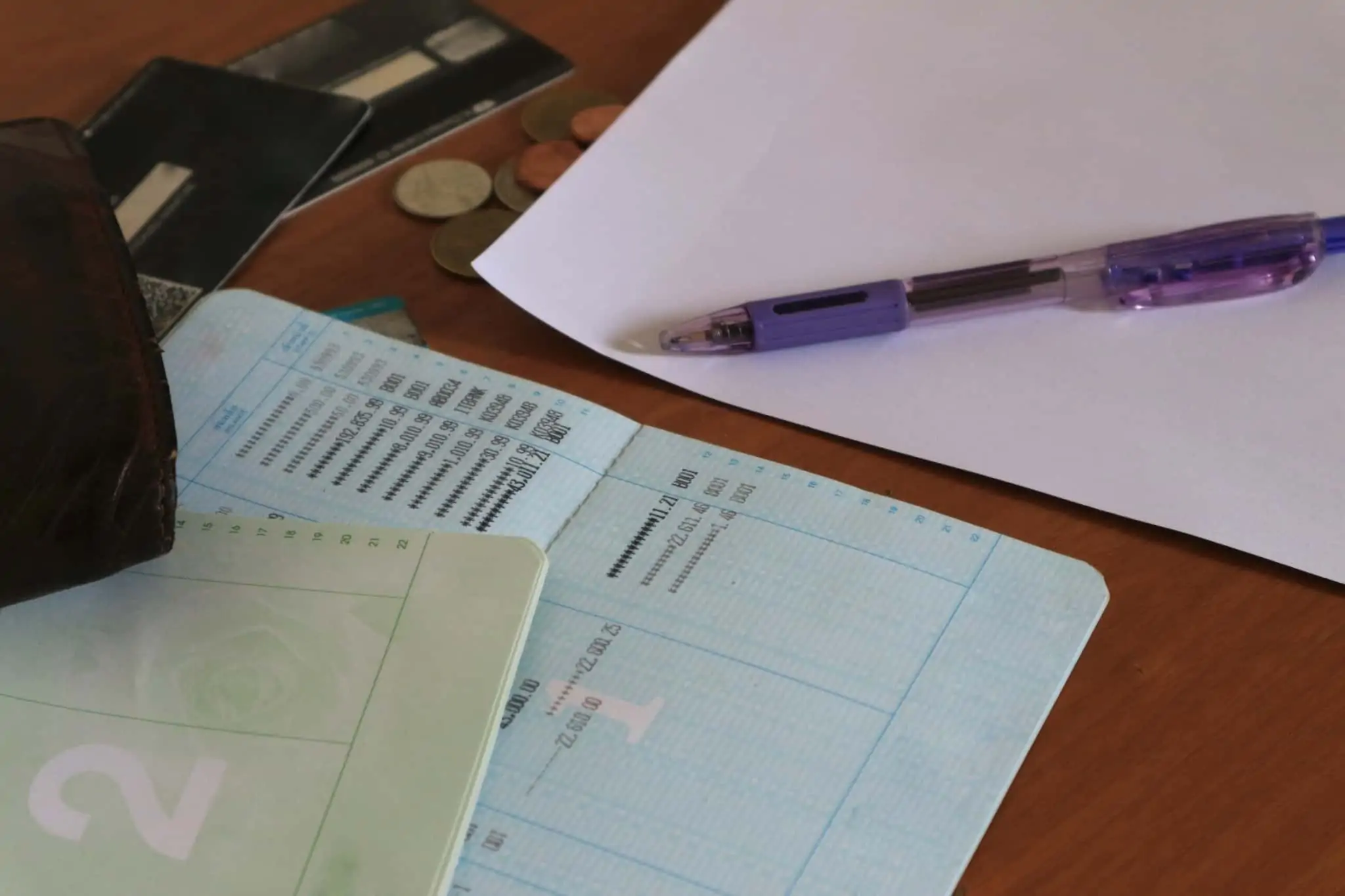 Qual a diferença entre saldo contabilístico, autorizado e disponível? mesa com caderneta com registo de mvimentos e saldos, e papel e caneta para verificar as contas.