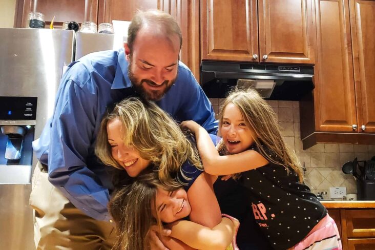 Família a abraçar-se na cozinha evocando as moratórias