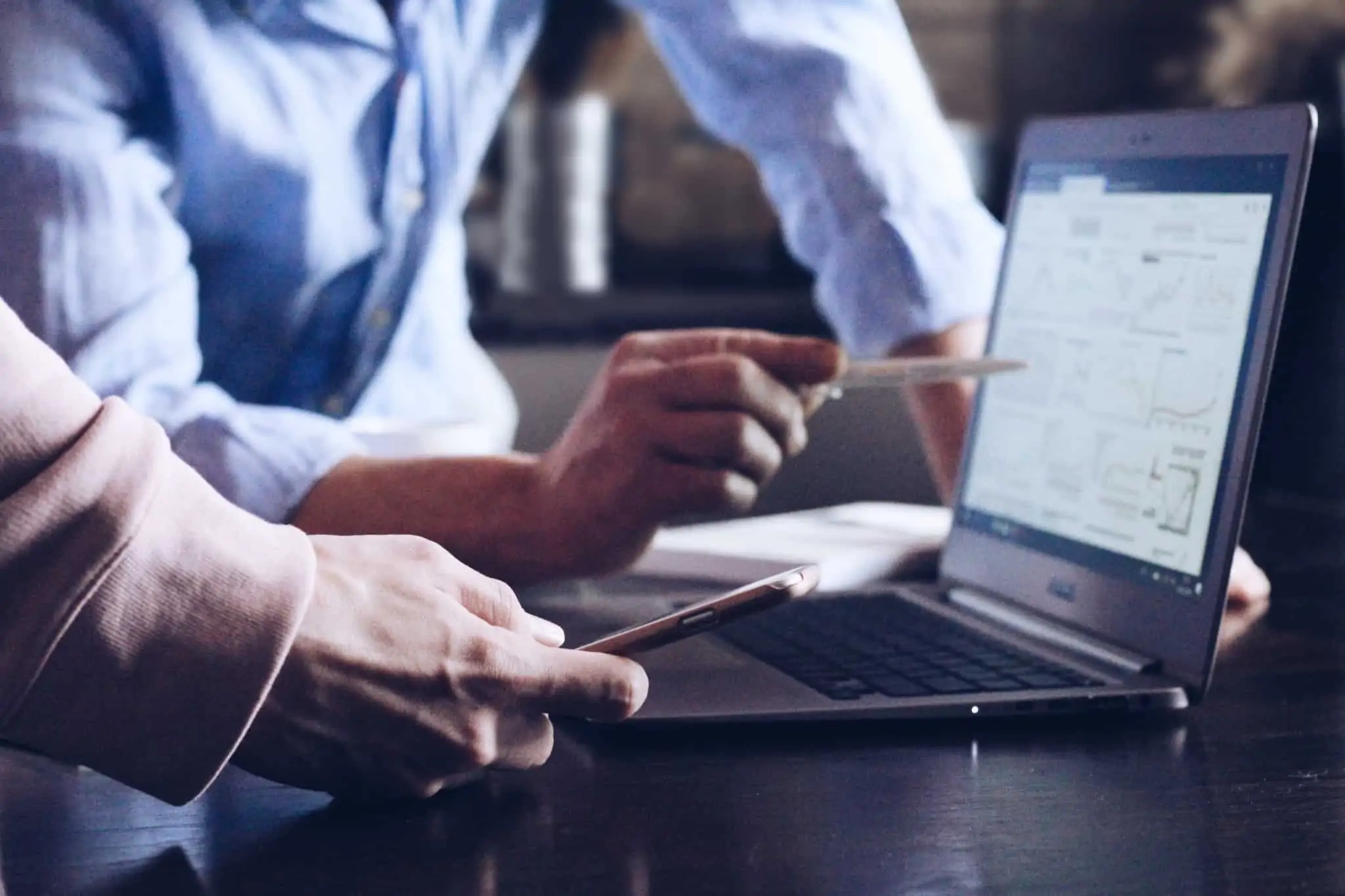 dois empresários consultam papéis e computador para tratar da contabilidade da empresa.