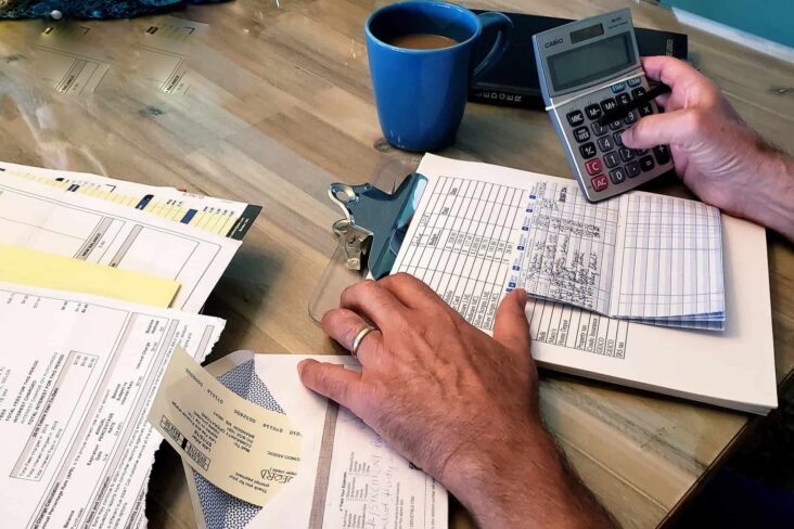 homem, de calculadora na mão, faz contas, revendo todas as contas e despesas que tem.