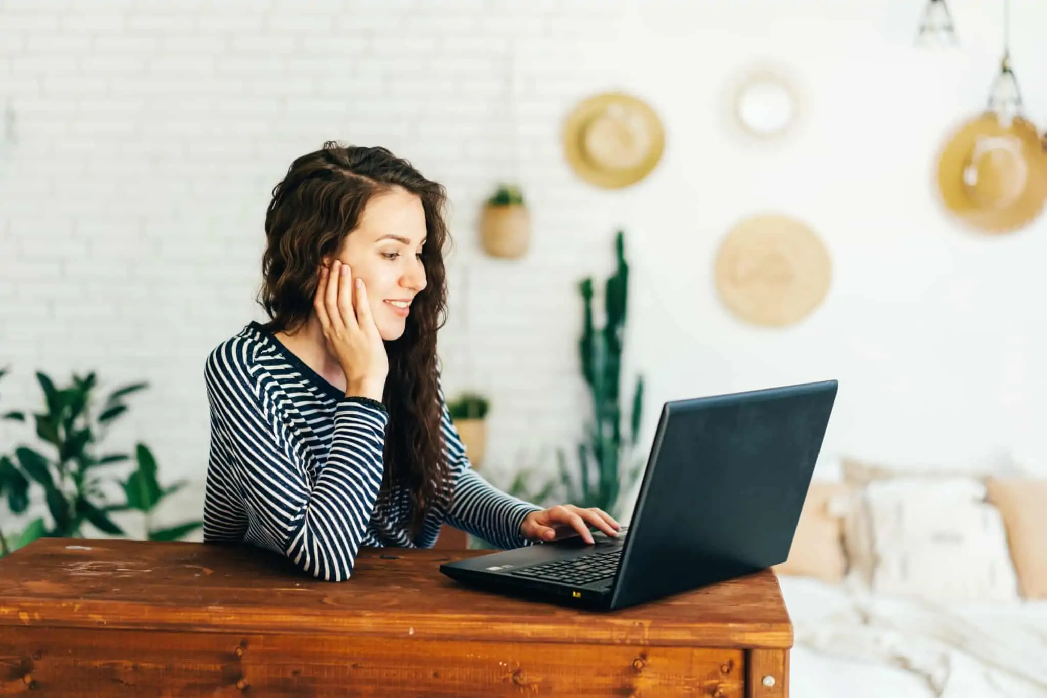 Entrada no mercado de trabalho: Guia de preparação jovem mulher sentada à mesa, ao computador, num escritório em casa, em ambiente acolhedor, prepara a entrada no mercado de trabalho
