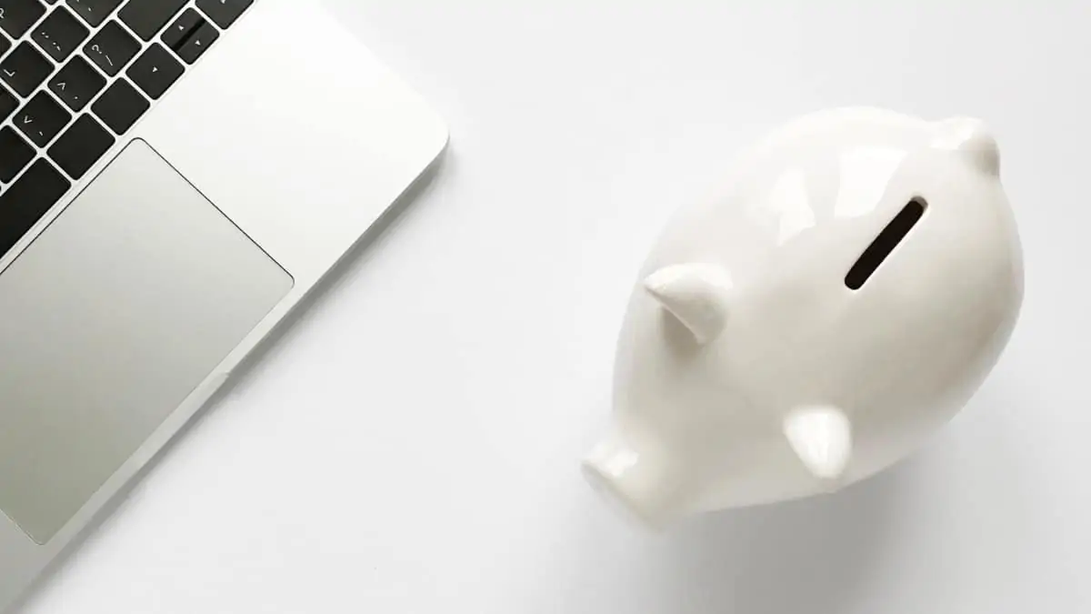 A sua empresa tem dívidas à Segurança Social? Saiba como regularizar Computador portátil com um mealheiro ao lado para pagar dívidas