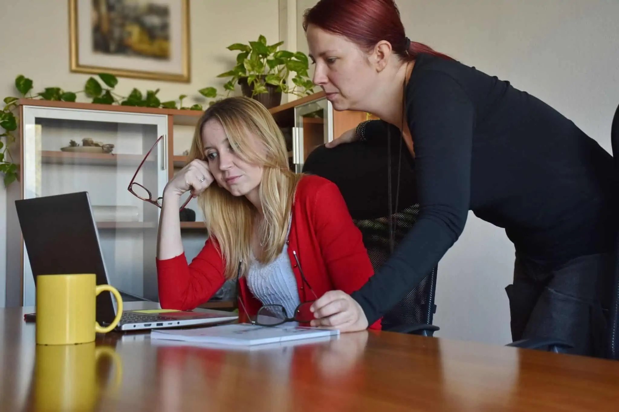 Empresa em dificuldades? O PER pode evitar o pior uma mulher sentada olha para o computador outra está reclinada sobre ela
