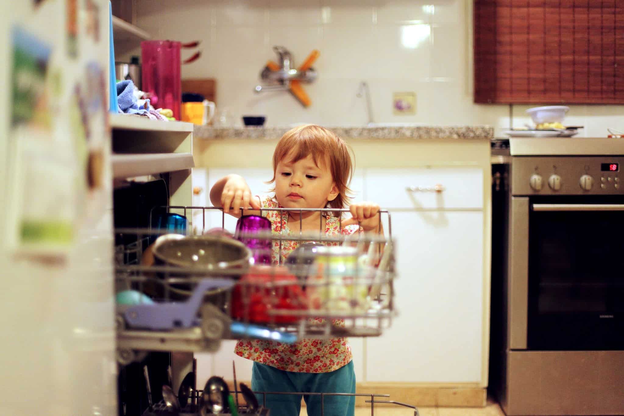 Criança mexe na máquina de lavar loiça a evocar consumo de energia e renováveis