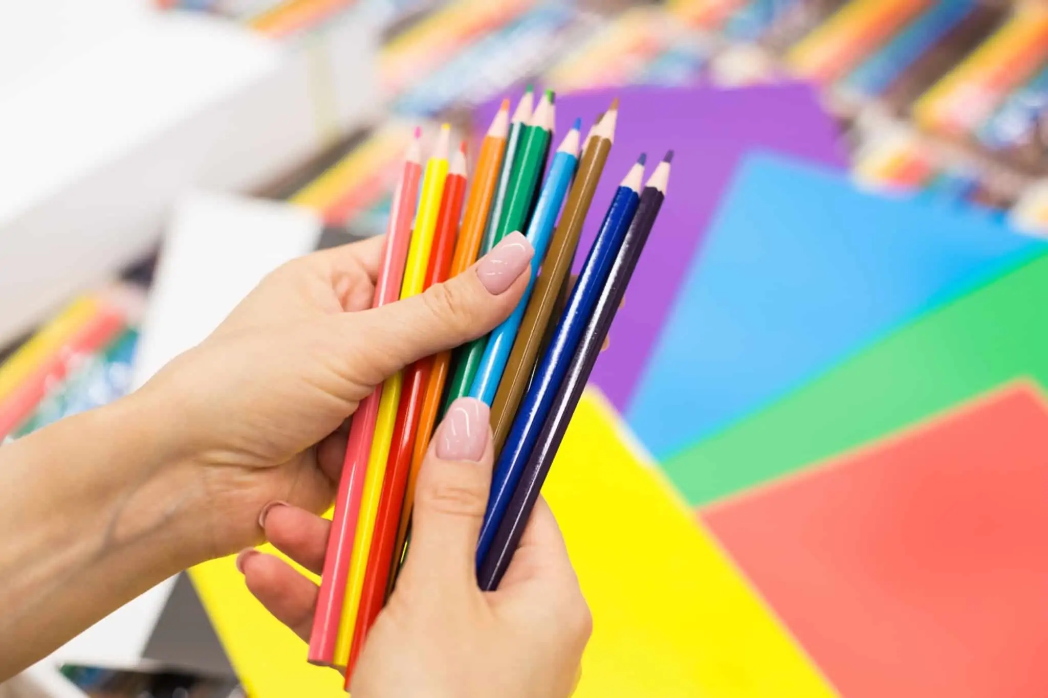 Regresso às aulas: Como preparar a carteira e as crianças? mãos de mulher com muitos lápis de cor, na preparação para o regresso às aulas