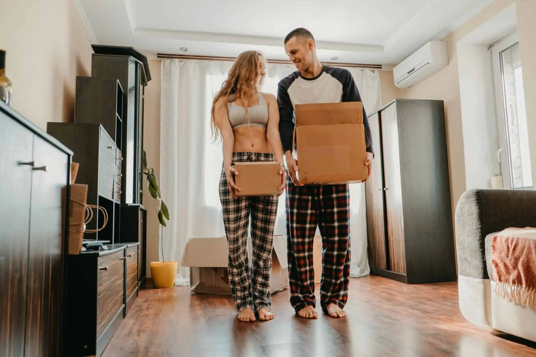 Mudar de casa: 11 assuntos que tem mesmo de tratar jovem casal, muito sorridente e cúmplice, carrega caixas de cartão de arrumação porque vão mudar de casa
