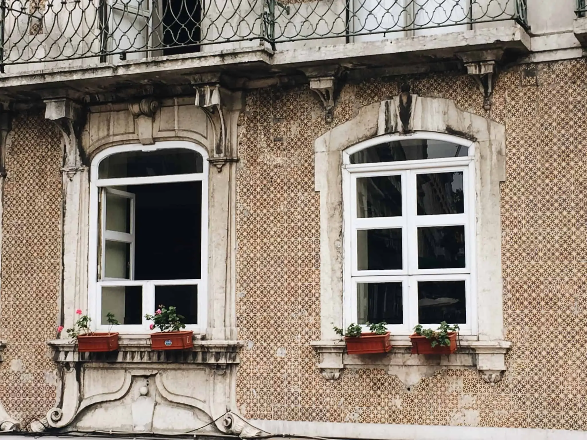 Comprar uma casa penhorada: Onde e como pode fazê-lo imagem com parte de uma fachada de um prédio antigo de Lisboa com duas janelas típicas
