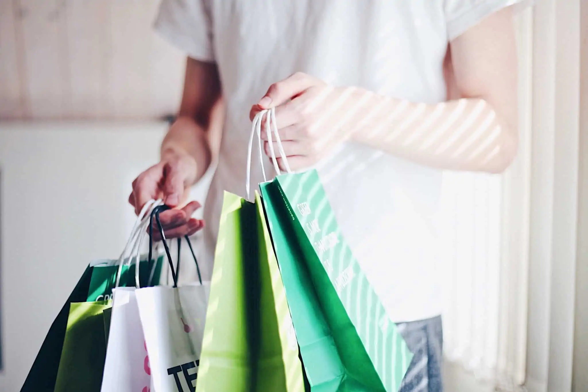 compras e dicas de poupança ilustradas por uma produção fotográfica que mostra a mão de uma jovem que segura muitos sacos de compras