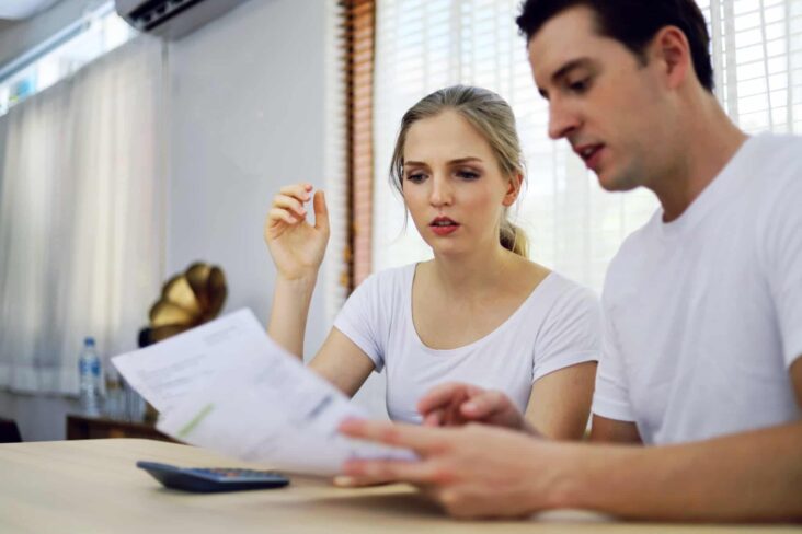 jovem casal analisa documentos de forma a reorganizar o seu orçamento familiar em tempos de crise pós-pandemia