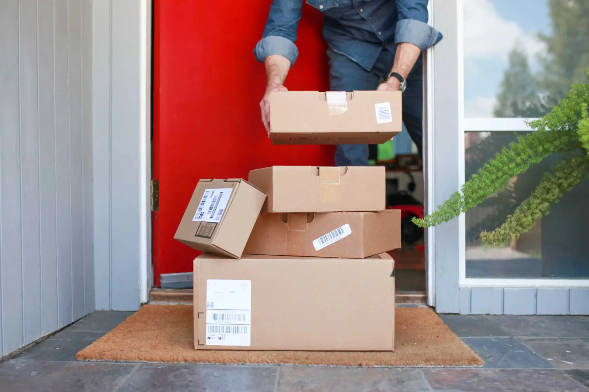 Problemas para desalfandegar uma encomenda? Saiba como proceder homem à prta de casa recebe um monte de encomendas, deixadas ali à porta, ao molho