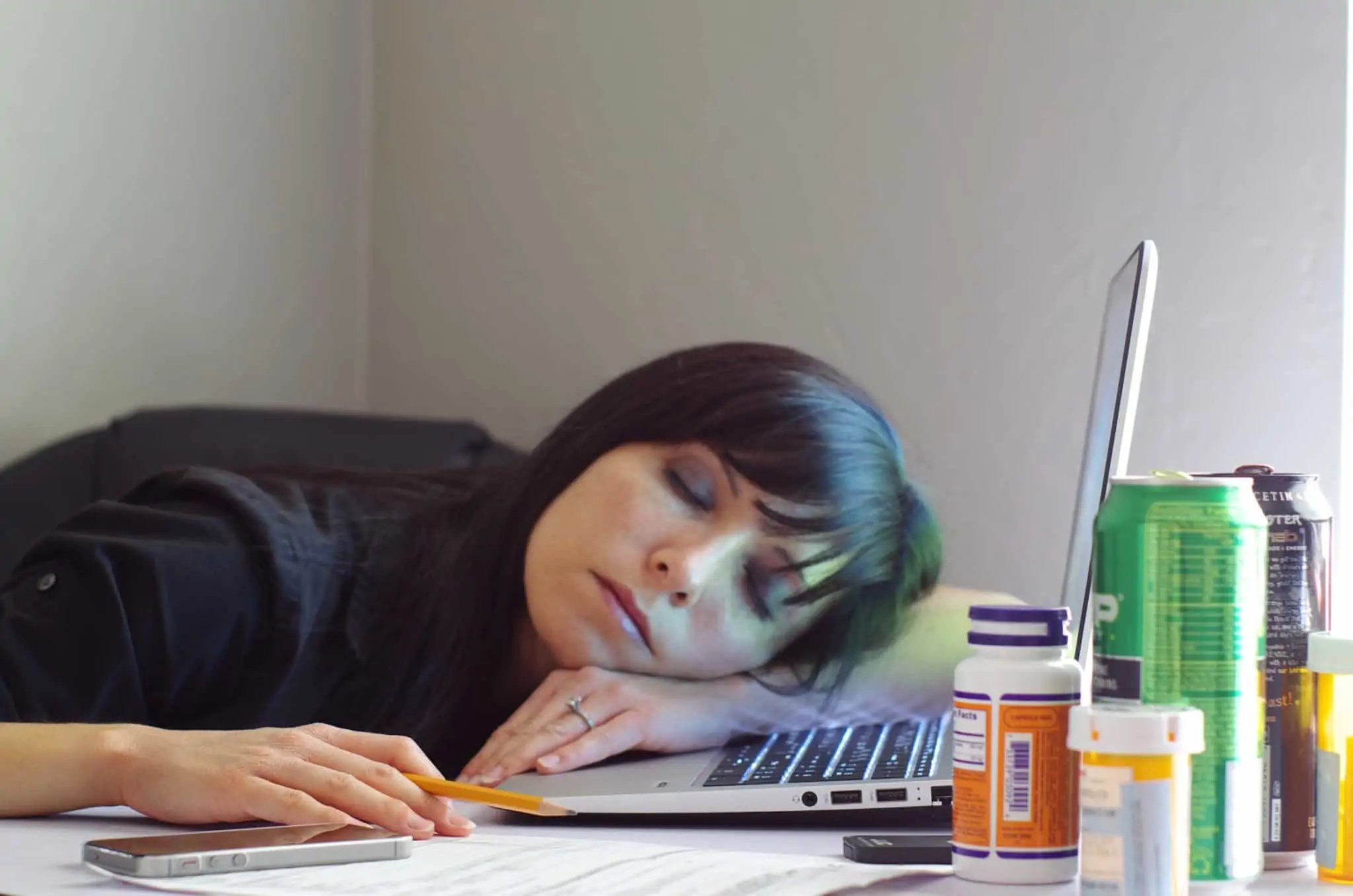Está a perder o foco? 10 ferramentas para aumentar a sua produtividade jovem mulher adormeceu em cima do seu computador portátil, rodeada de prodytos para ter mais energia e conseguir manter o foco e produtividade