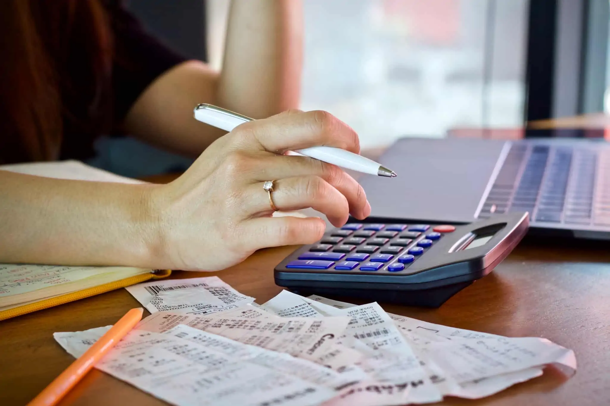 Ajudas de custo: Que valores são praticados e quando são tributadas? pagamento de ajudas de custo ilustrado com uma jovem mulher que consulota faturas e faz contas na calculadora