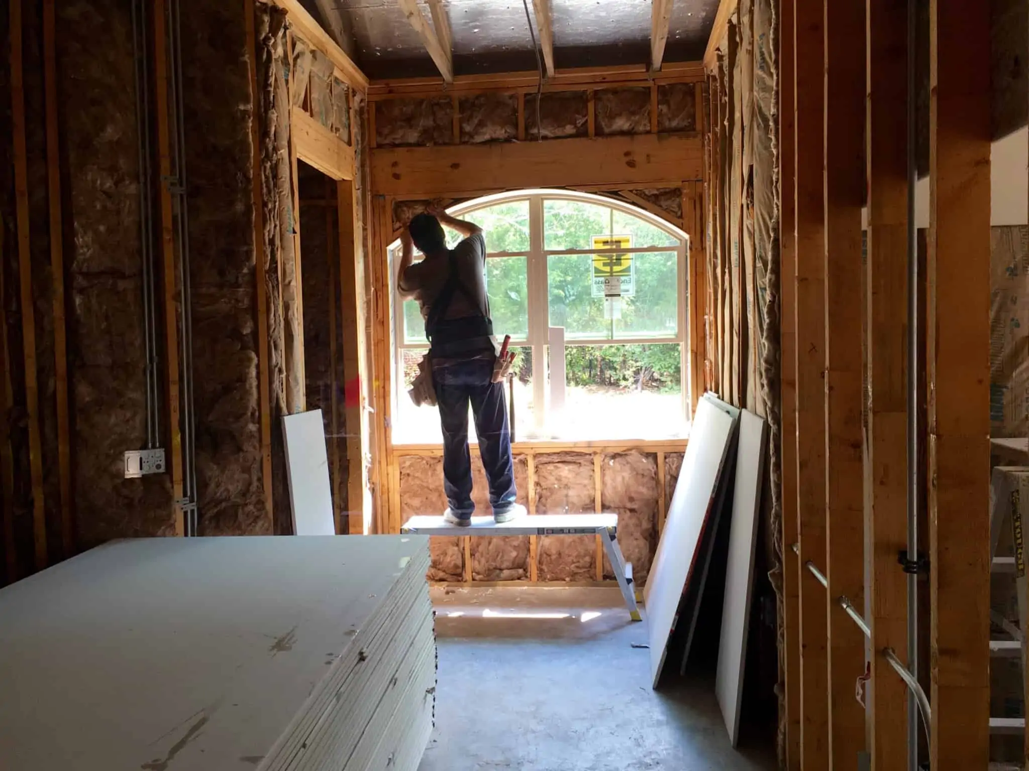 homem a construir o interior de uma casa, trabalha junto a uma janela
