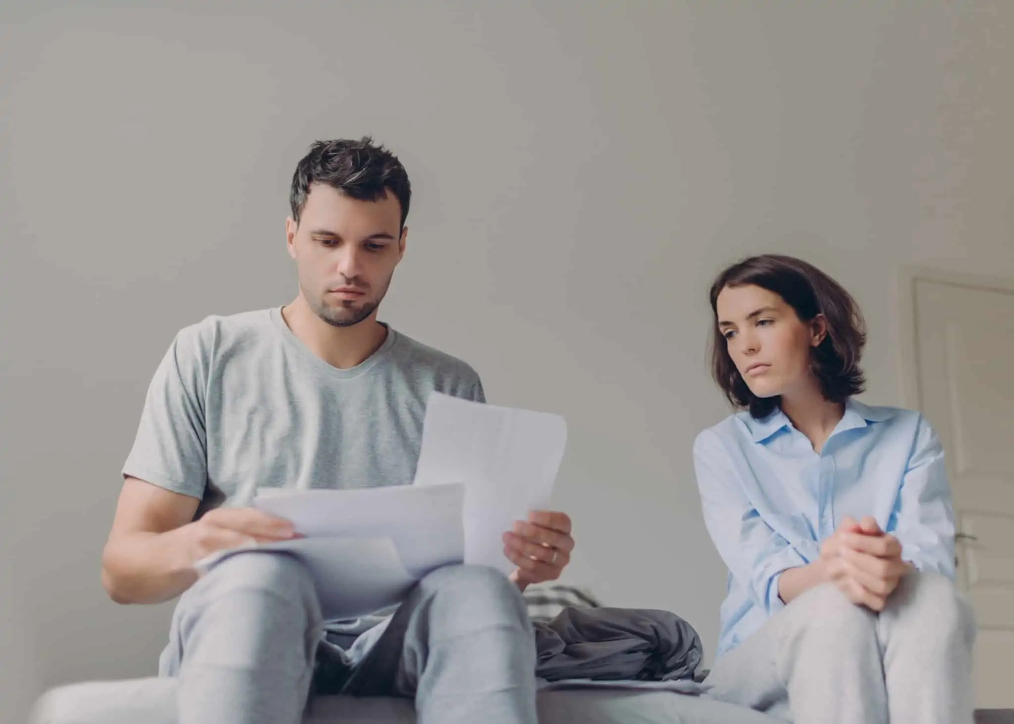 Extrato de comissões: O que é, o que deve conter e como reduzir custos casal consulta, com um ar preocpado e pesado, os documentos com exttratos de comissões bancárias