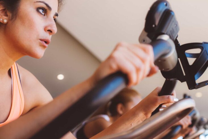 jovem mulher a participar numa aula de grupo, de bicicleta, num ginásio