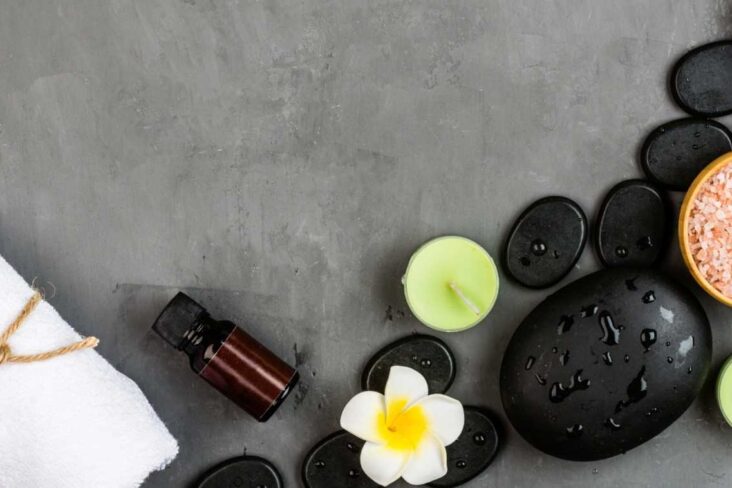 pedras de spa dispostas no chão rodeada de flores num experiência para ter uma vida mais feliz