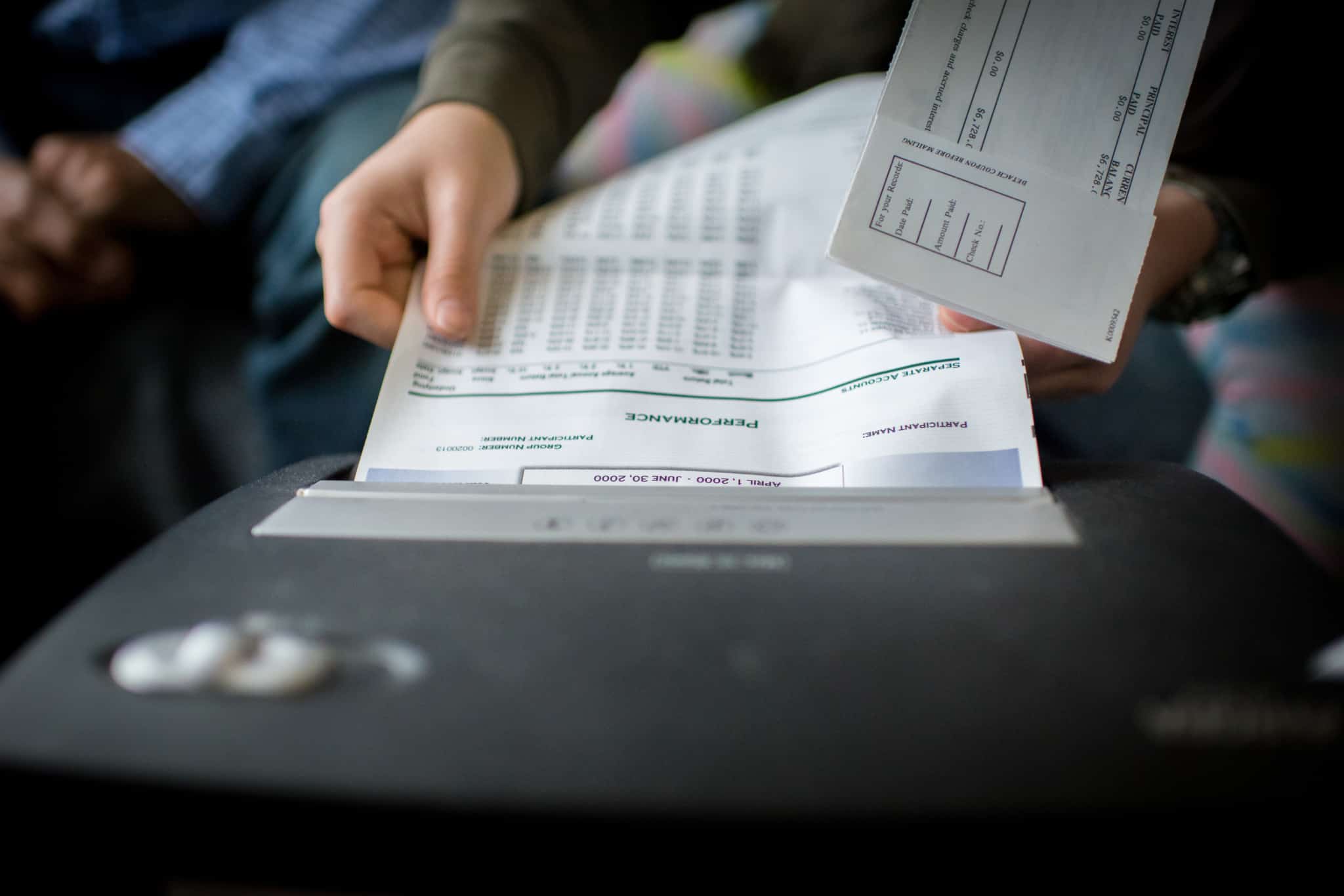 Sabe que documentos deve rasgar antes de os deitar fora? mulher insere documentos pessoais, no caso são extratos, numa máquina de triturar papel. destroi por questões de segurança