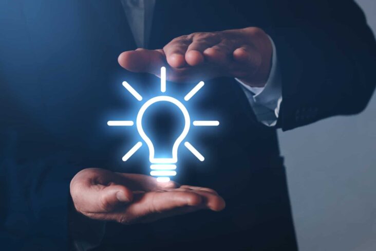 produção fotográfica de um homem que segura entre as mãos uma lâmpada (em símbolo) de alto brilho