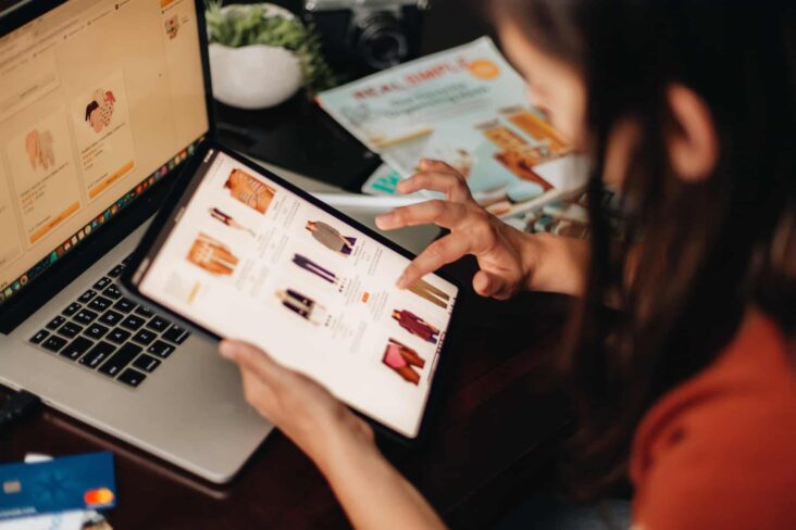 jovem mulher faz compras online, recorrendo ao seu tablet e computador portátil