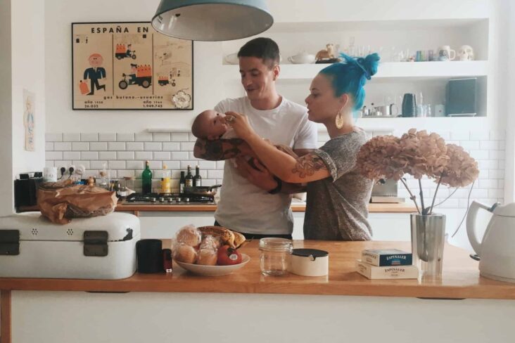 jovem casal segura bebé, em casa, na cozinha, muito felizes