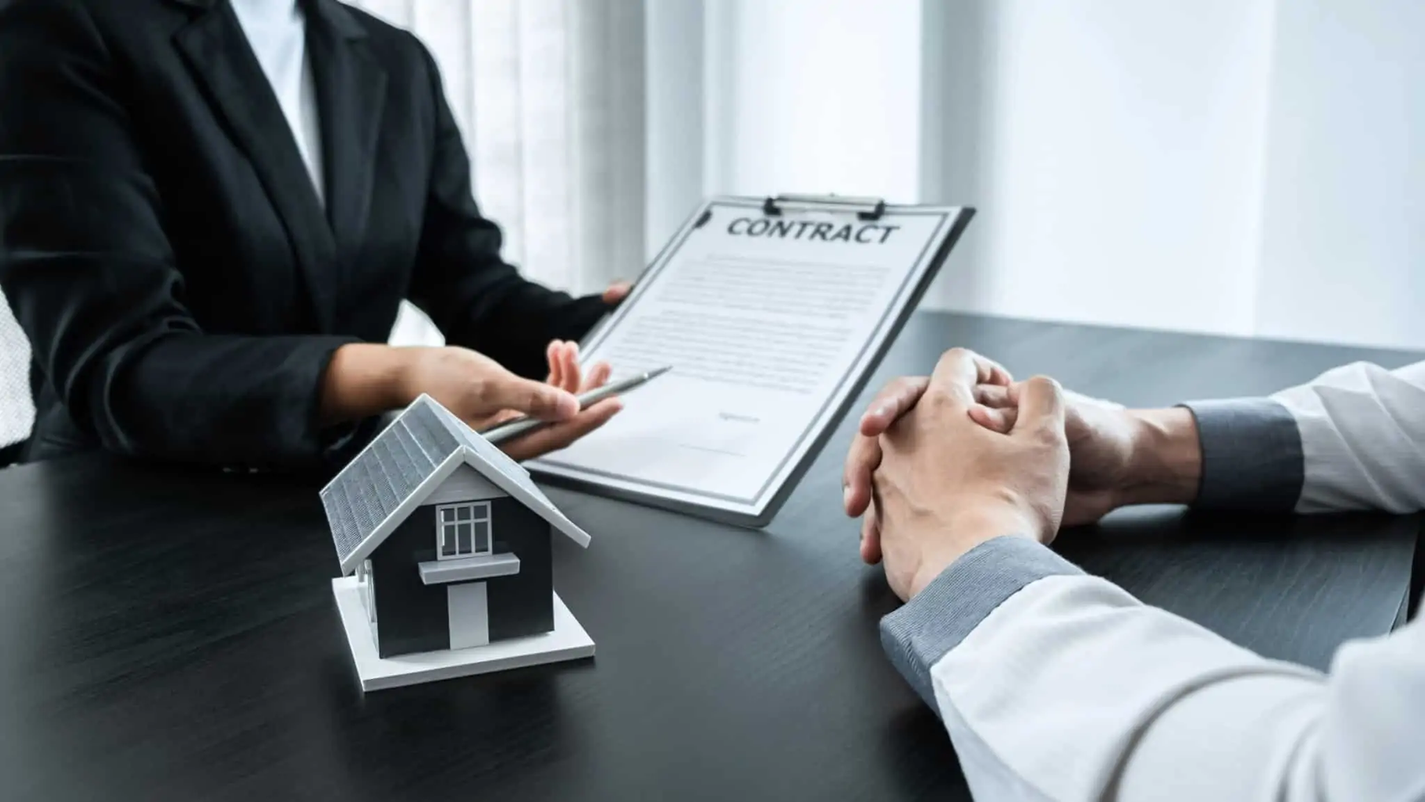 duas pessoas com um contrato no meio e uma casa em destaque