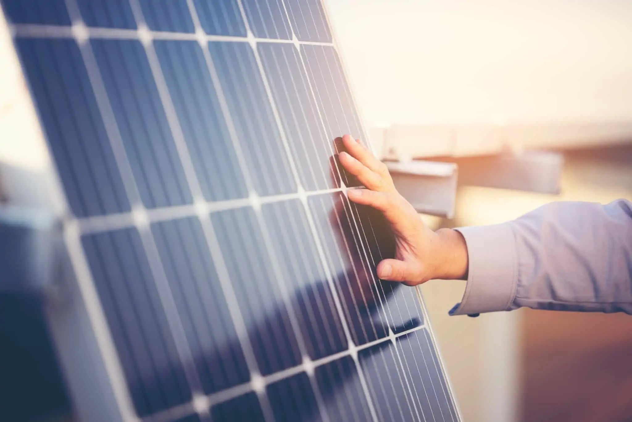 Vender excedente de painéis solares compensa? Saiba que passos dar mão de um homem jovem toca num painel solar