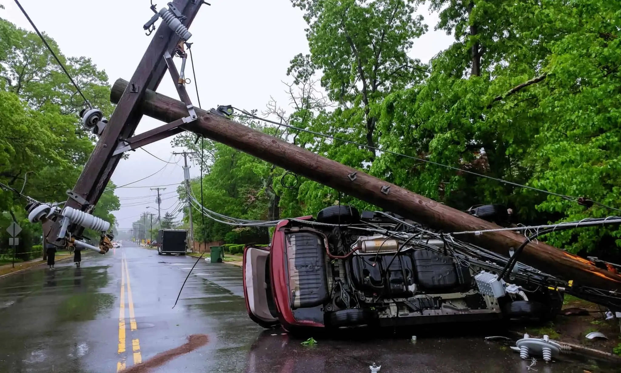 poste da eletricidade cai sobre carro na estrada, fruto do mau tempo, causando estragos avultados