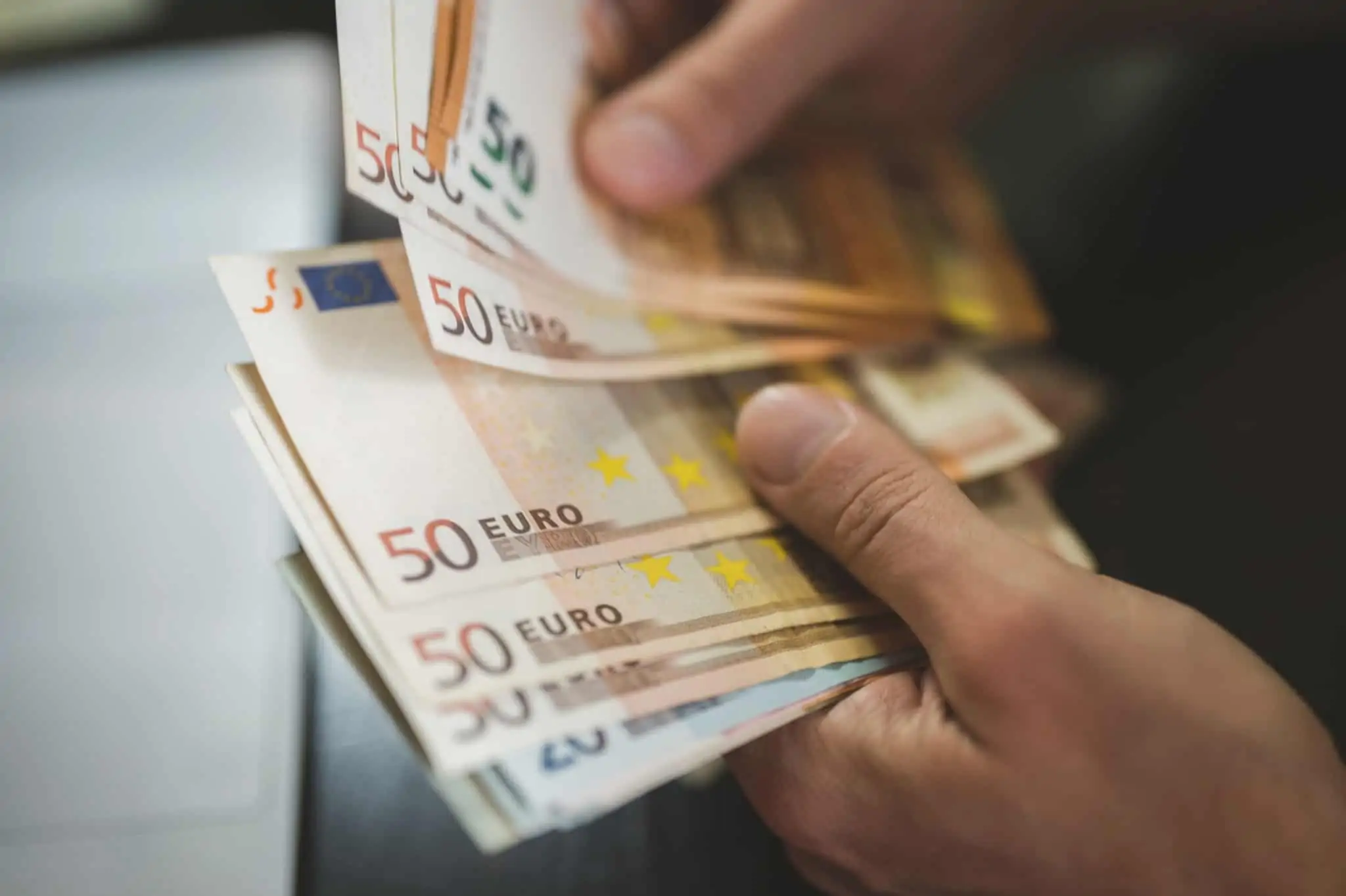 Conta caucionada: O que é e para que serve mãos de um jovem seguram notas de 50 e 20 euros