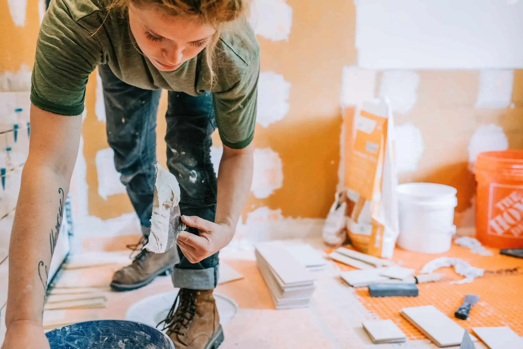 Licença da câmara para obras em casa: Quando é preciso obter? jovem mulher a fazer obras em casa, a aplicar estuque e rodeada de ferramentas e produtos para as obras