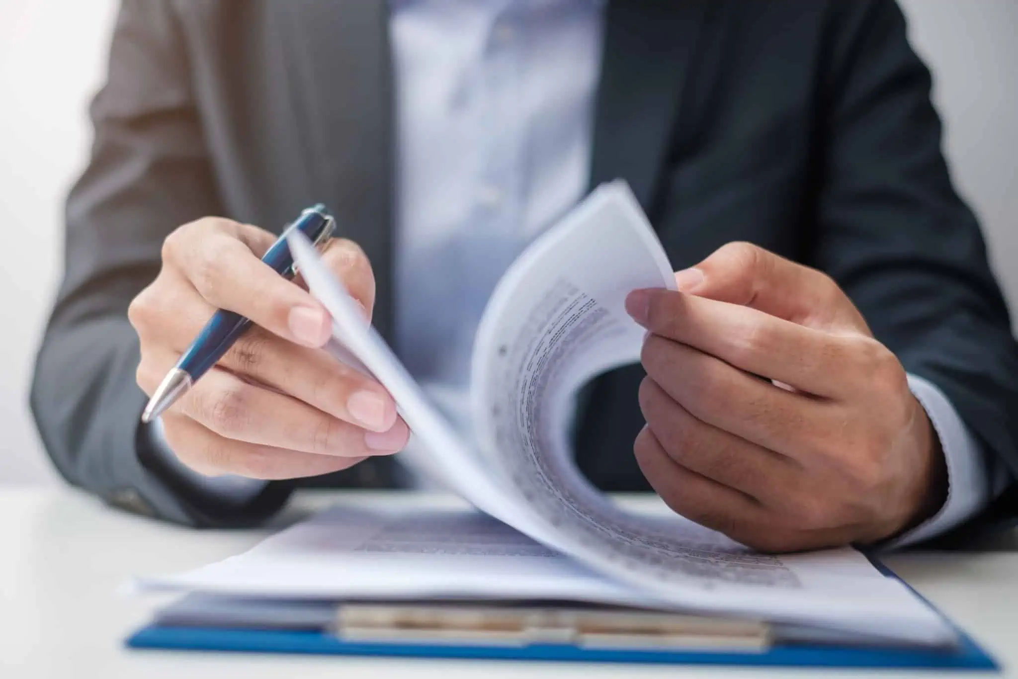 Rescisão do contrato de trabalho: direitos e deveres Imagem de uma pessoa sentada à mesa a folhear um contrato de crédito - analisar taxas de juro tan e taeg