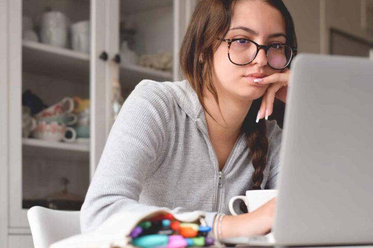 jovem mulher, estudante universitária, concentrada e ficada, a estudar no computador portátil