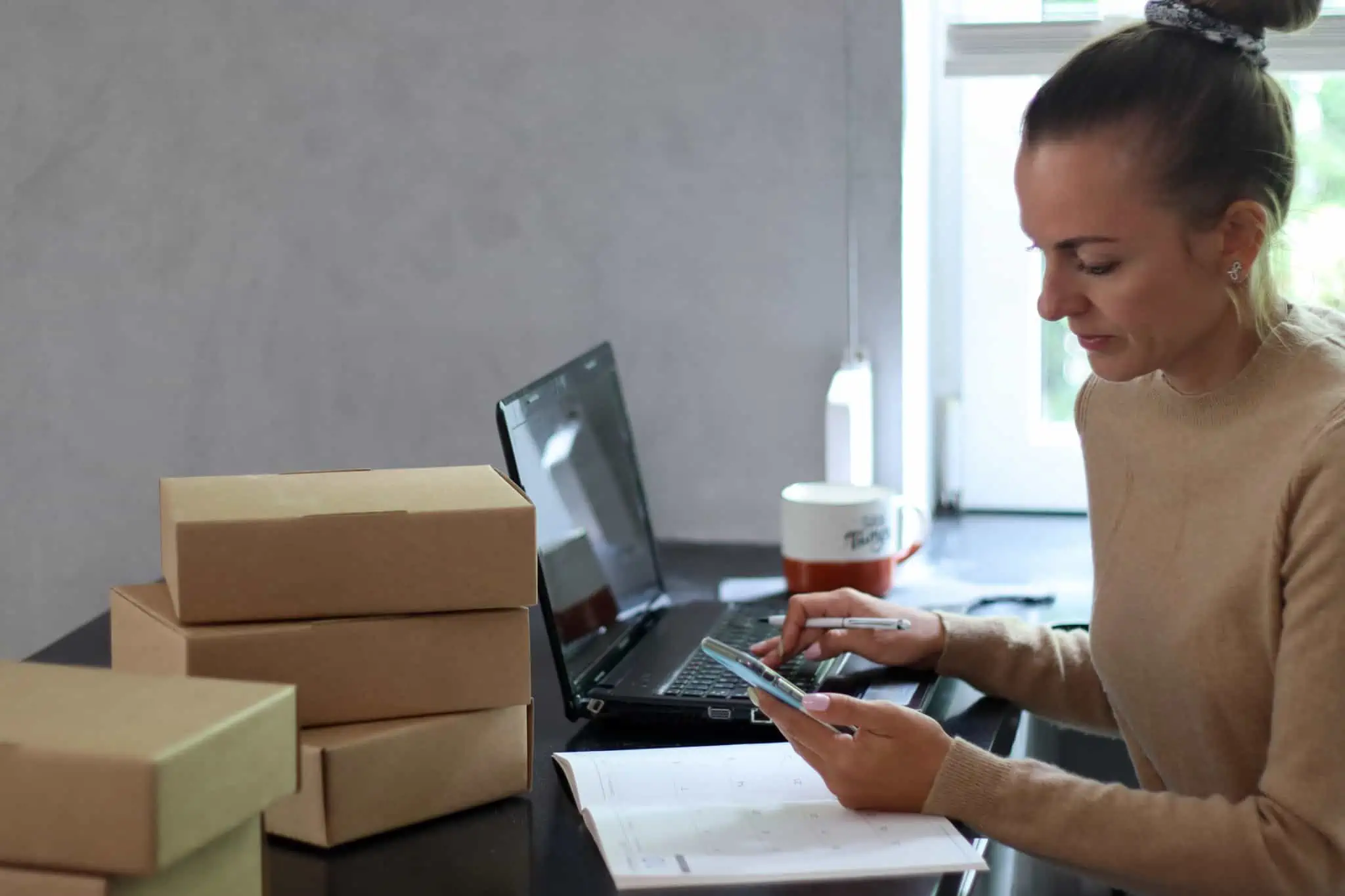7 formas criativas de ganhar dinheiro online jovem mulher consulta telemóvel e computador portátil para gerir o seu negócio com que vai ganhar dinheiro online