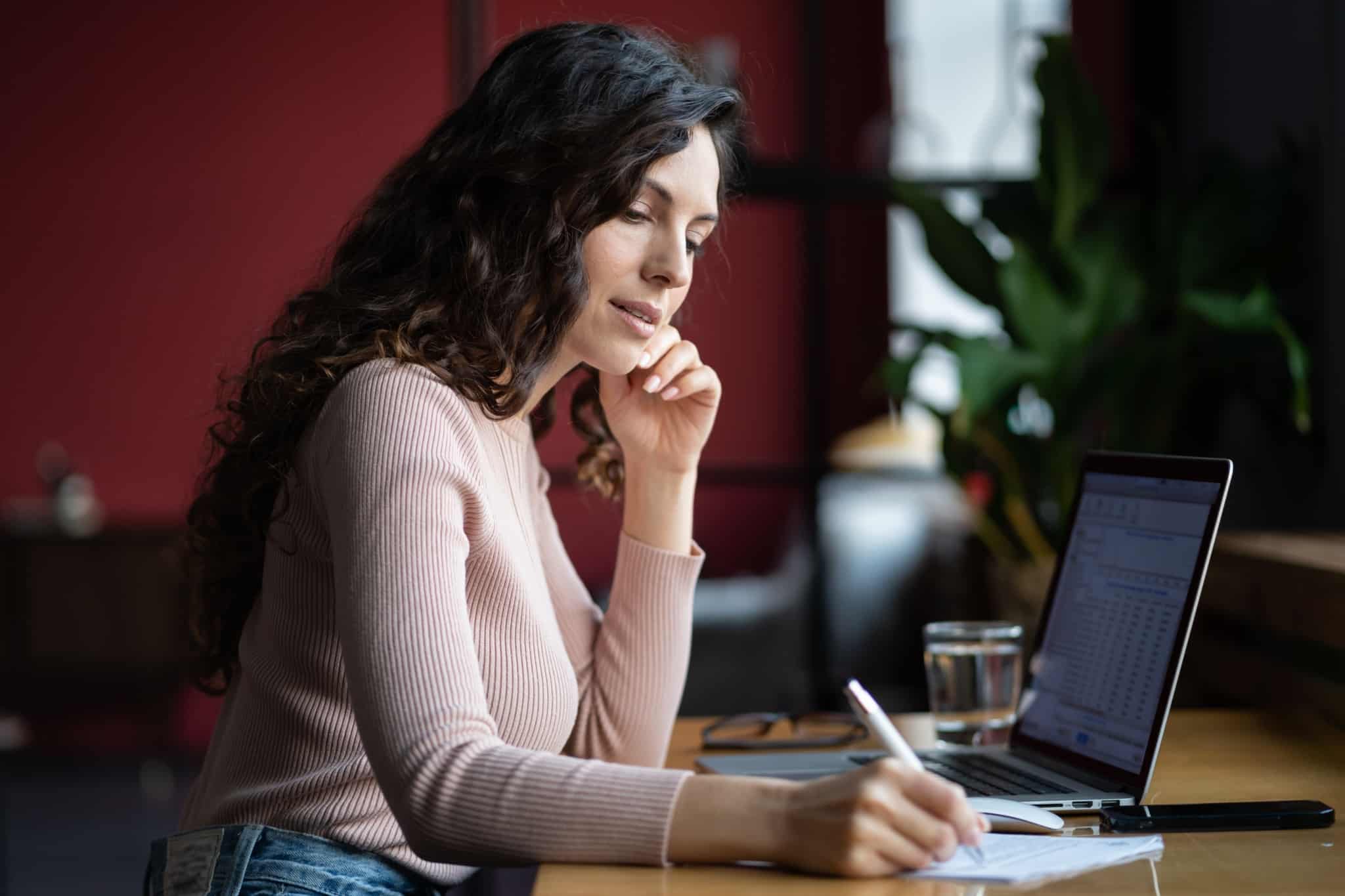 Dispensa de retenção de IRS para recibos verdes em 2023: Como funciona jovem mulher faz contas e preenche o IRS para profisionais que passam recibos verdes por trabalharem por conta própria