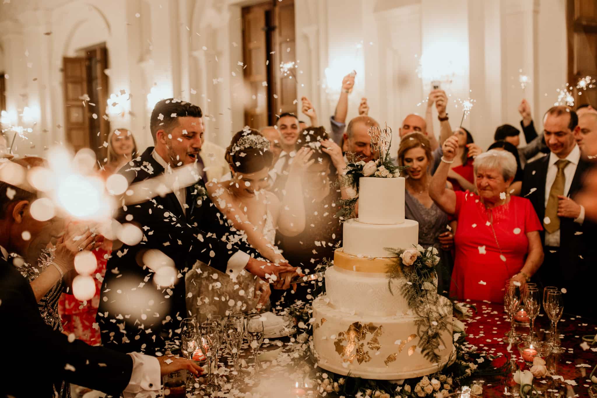 Casamento à porta? O que deve ter em conta neste orçamento especial casamento vivido em grande ambiente de festa com os noivos rodeados pela família e amigos que brindam enquanto eles se preparam para cortar o bolo